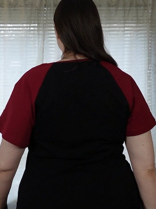 Woman in a black T-shirt with red raglan sleeves, back view