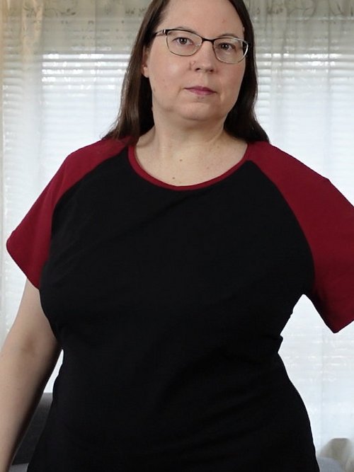 Woman in a black T-shirt with red raglan sleeves, one arm extended