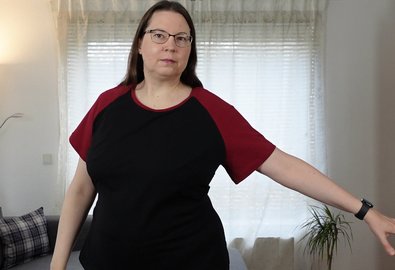 Woman in a black T-shirt with red raglan sleeves, one arm extended